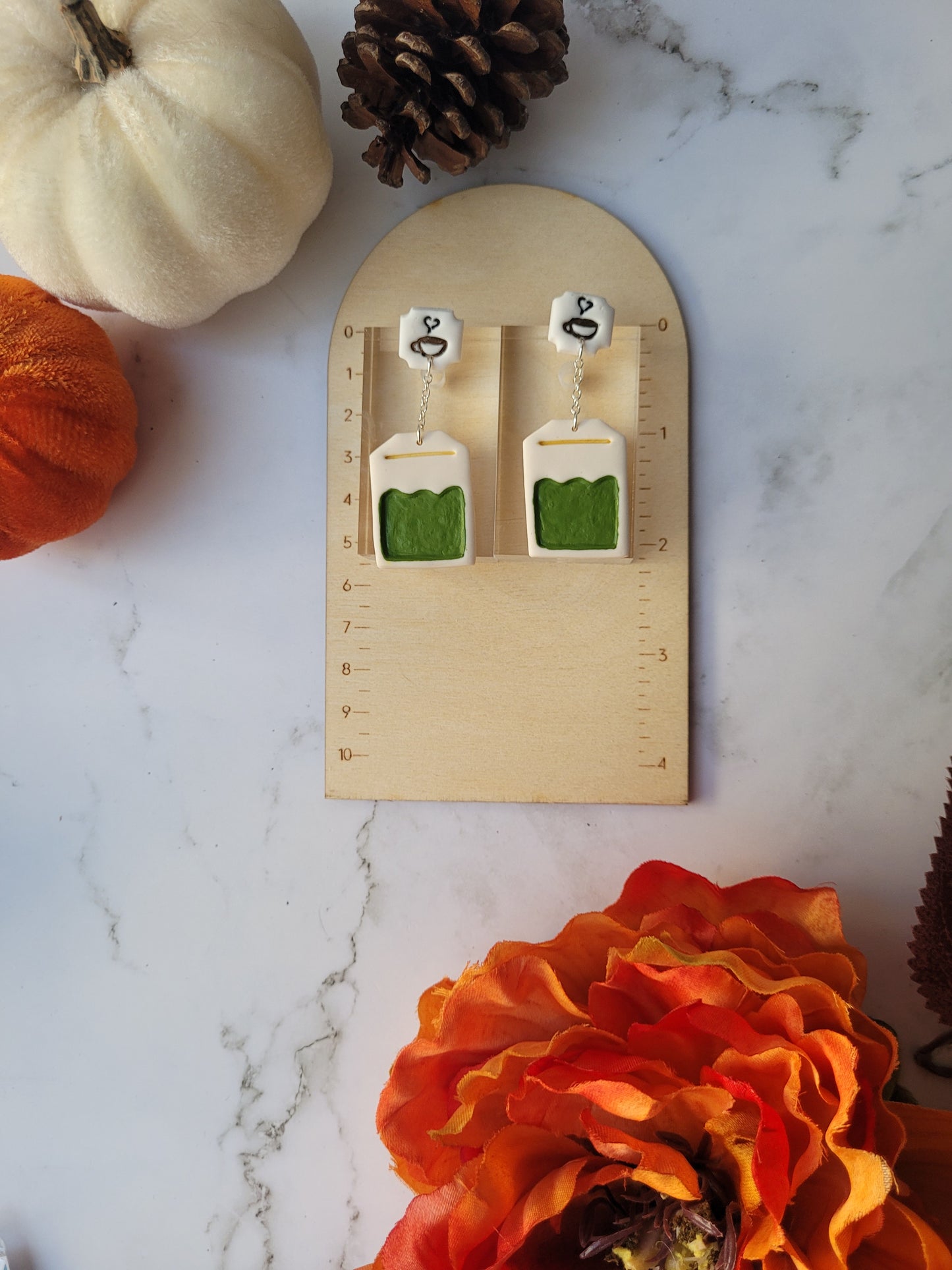 green tea bag shaped dangle earrings on a ruler background .