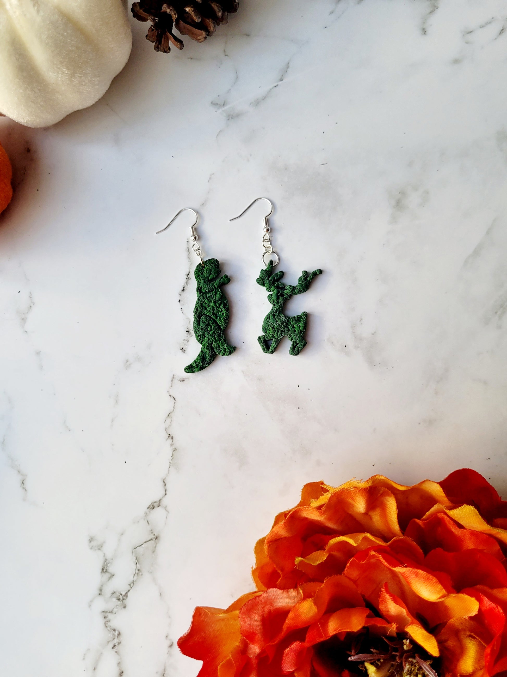 Edward Scissorhands themed topiary earrings on a marble background.