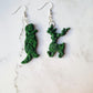 close up of Edward Scissorhands themed topiary earrings on a marble background.