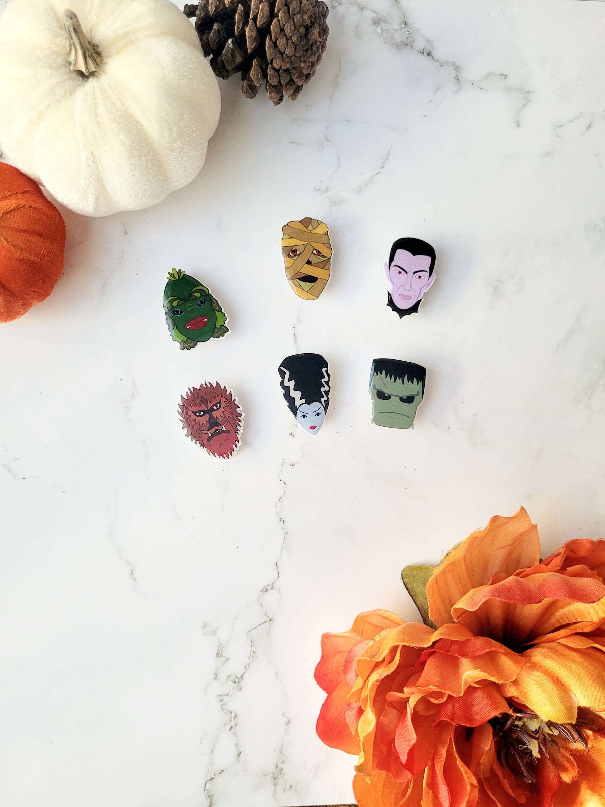 6 universal monster head lapel pins on a marble background 