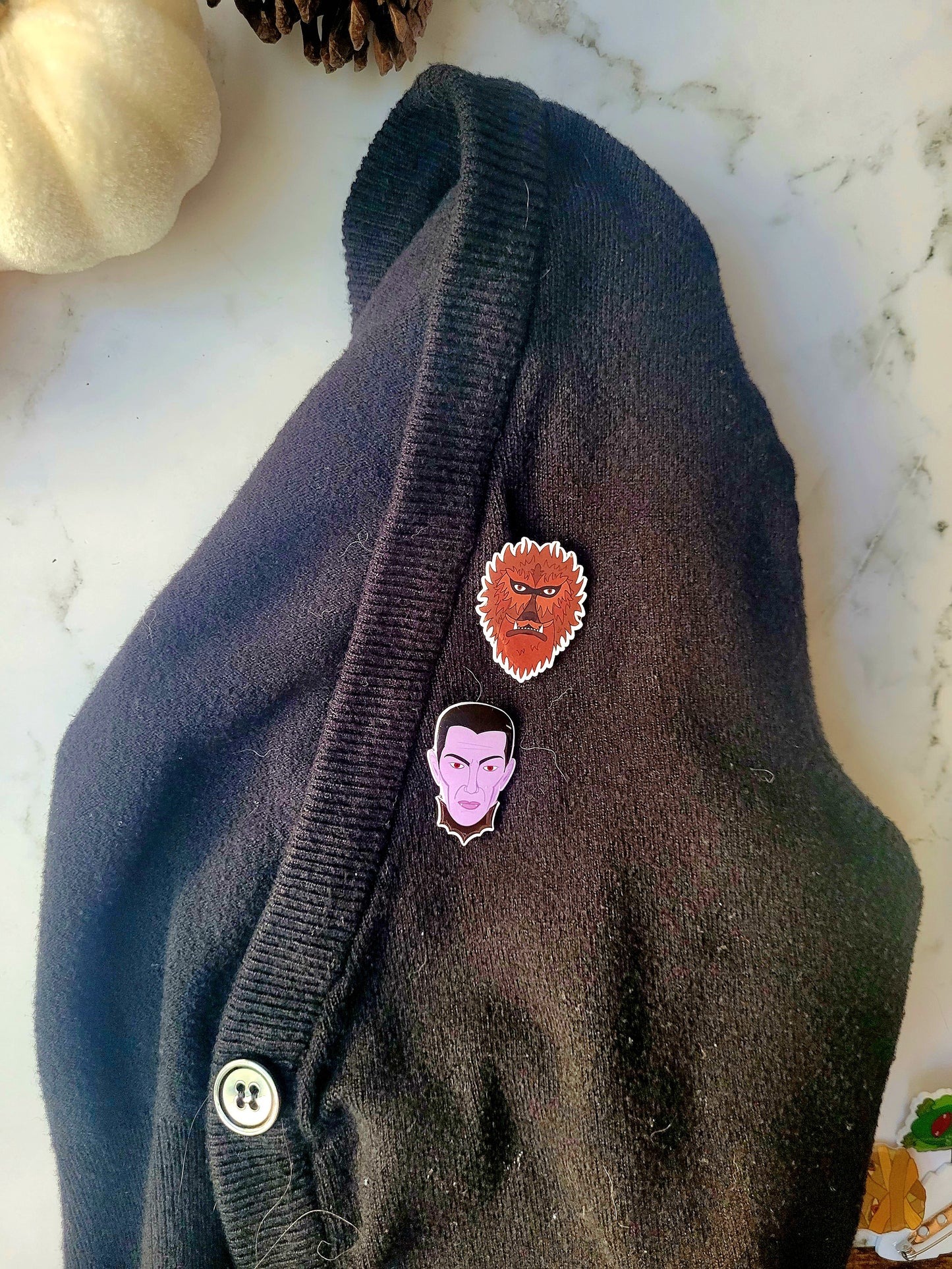 Wolfman and dracula monster pins on a black cardigan 