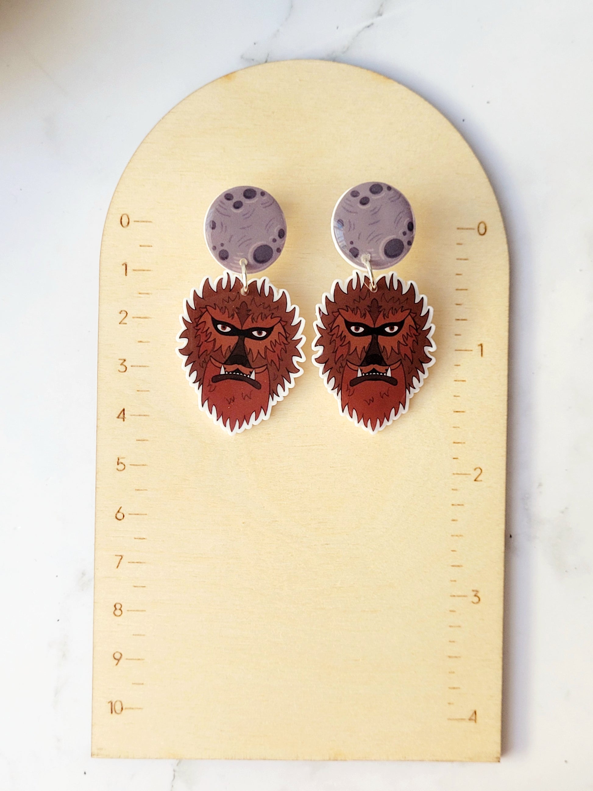 Wolfman head dangle earring with moon stud on a ruler background