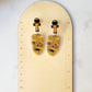 close up of mummy head dangle earrings with ankh stud on a ruler background