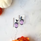 dracula dangle earrings on a white marble background with fall foliage. 