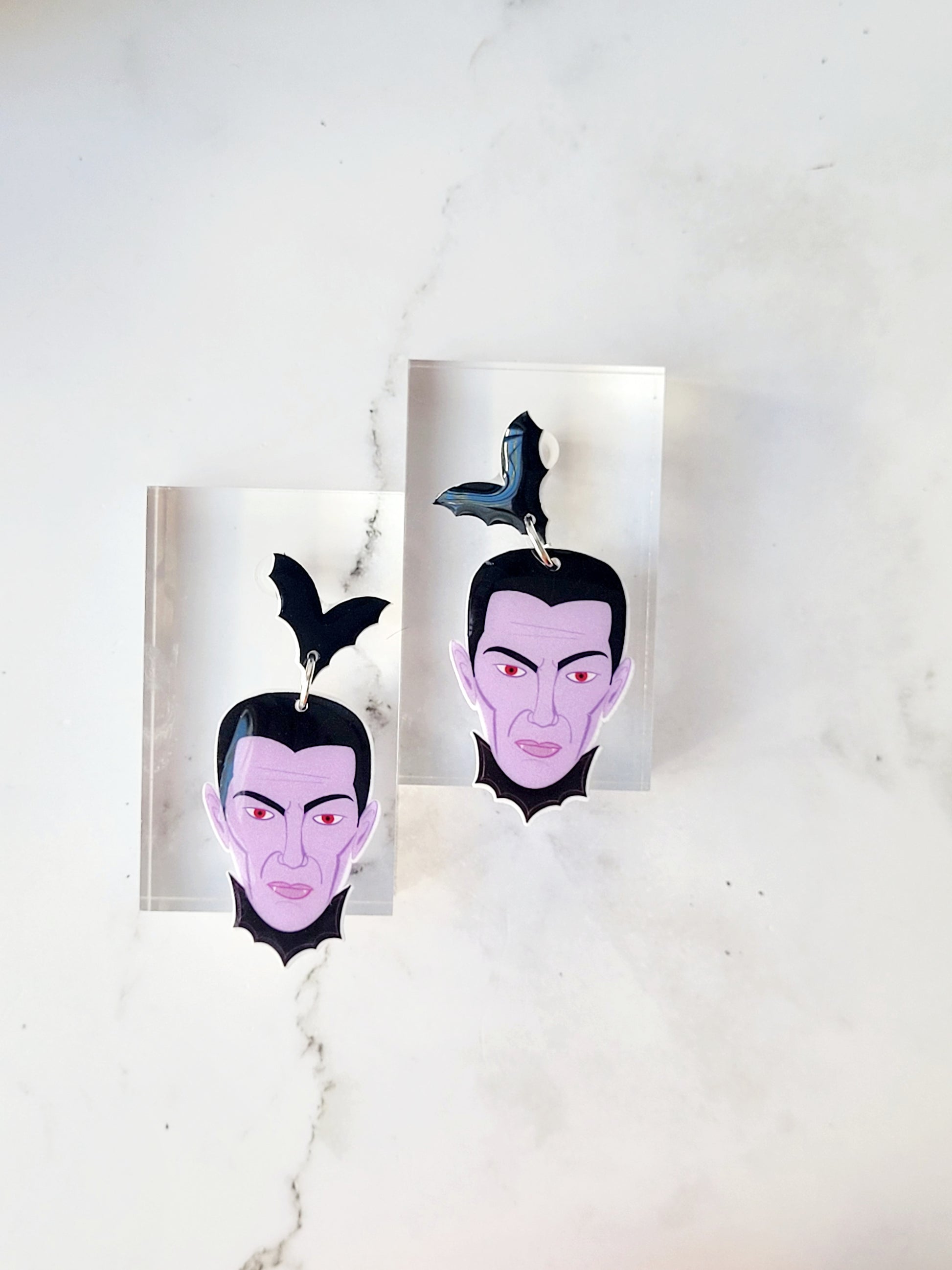 close up of dracula dangle earrings on a white marble background 