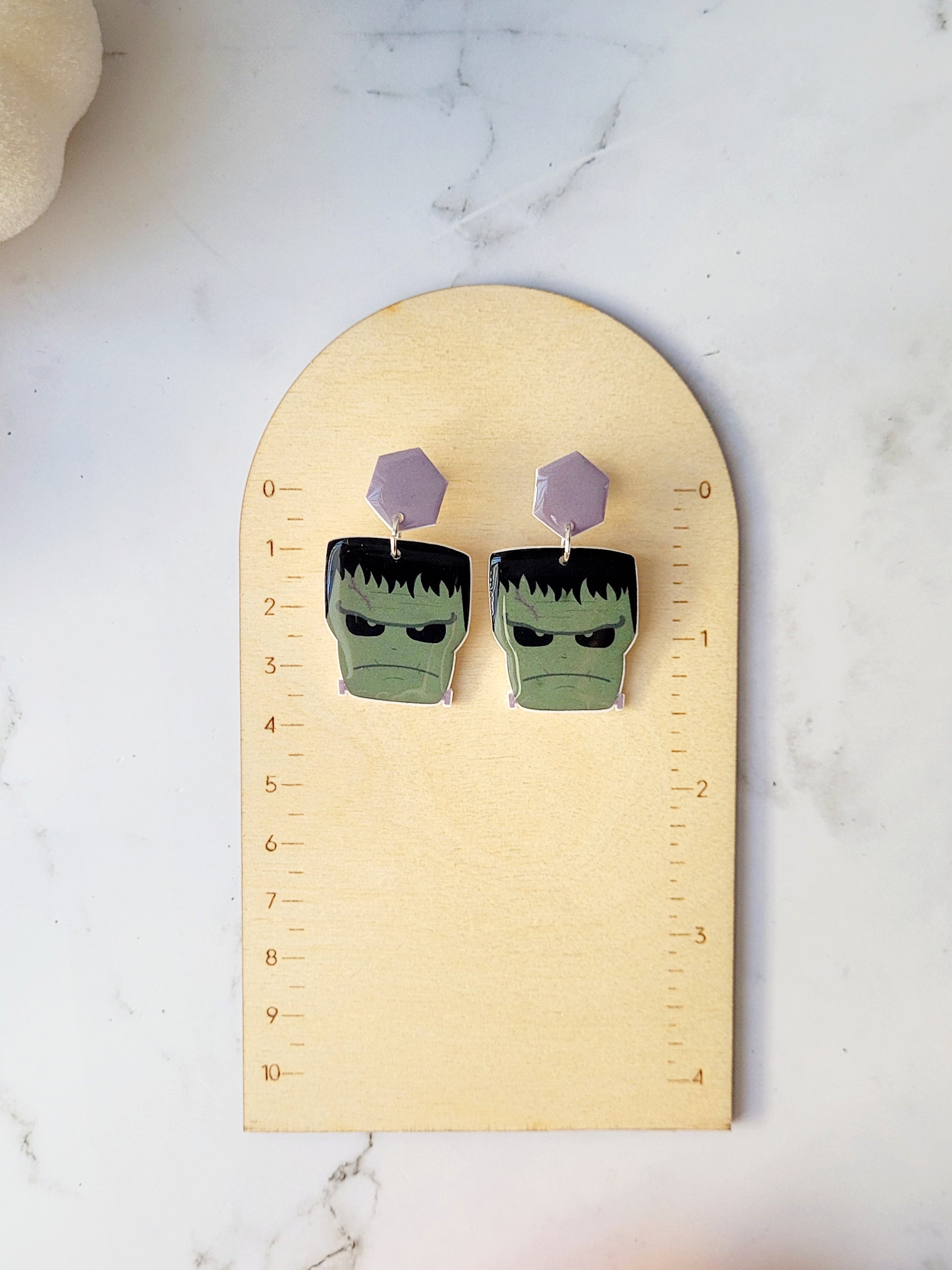 close up of Frankenstein dangle earrings on a ruler background