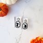 Beetlejuice silhouette earrings on a marble background. 