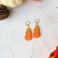 Triple stack pumpkin earrings on a marble background with fall foliage. 