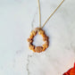close up of fall harvest themed teardrop necklace on a marble background