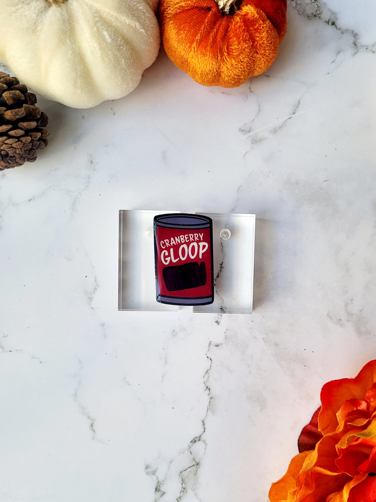 close up of Cranberry sauce pin on a marble background with fall foliage. 