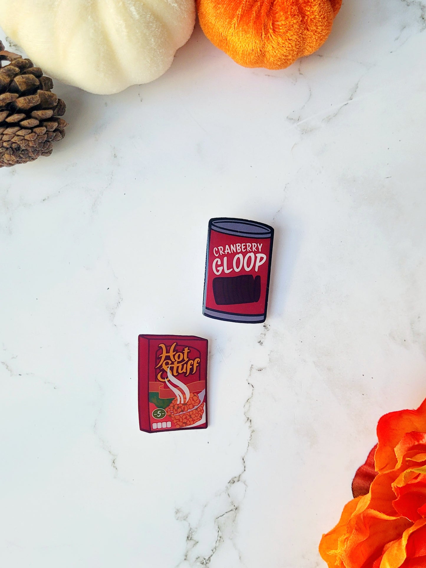 Cranberry sauce and stuffing box pins on a marble background with fall foliage. 