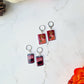 Cranberry sauce and stuffing box earrings on a marble background with fall foliage. 