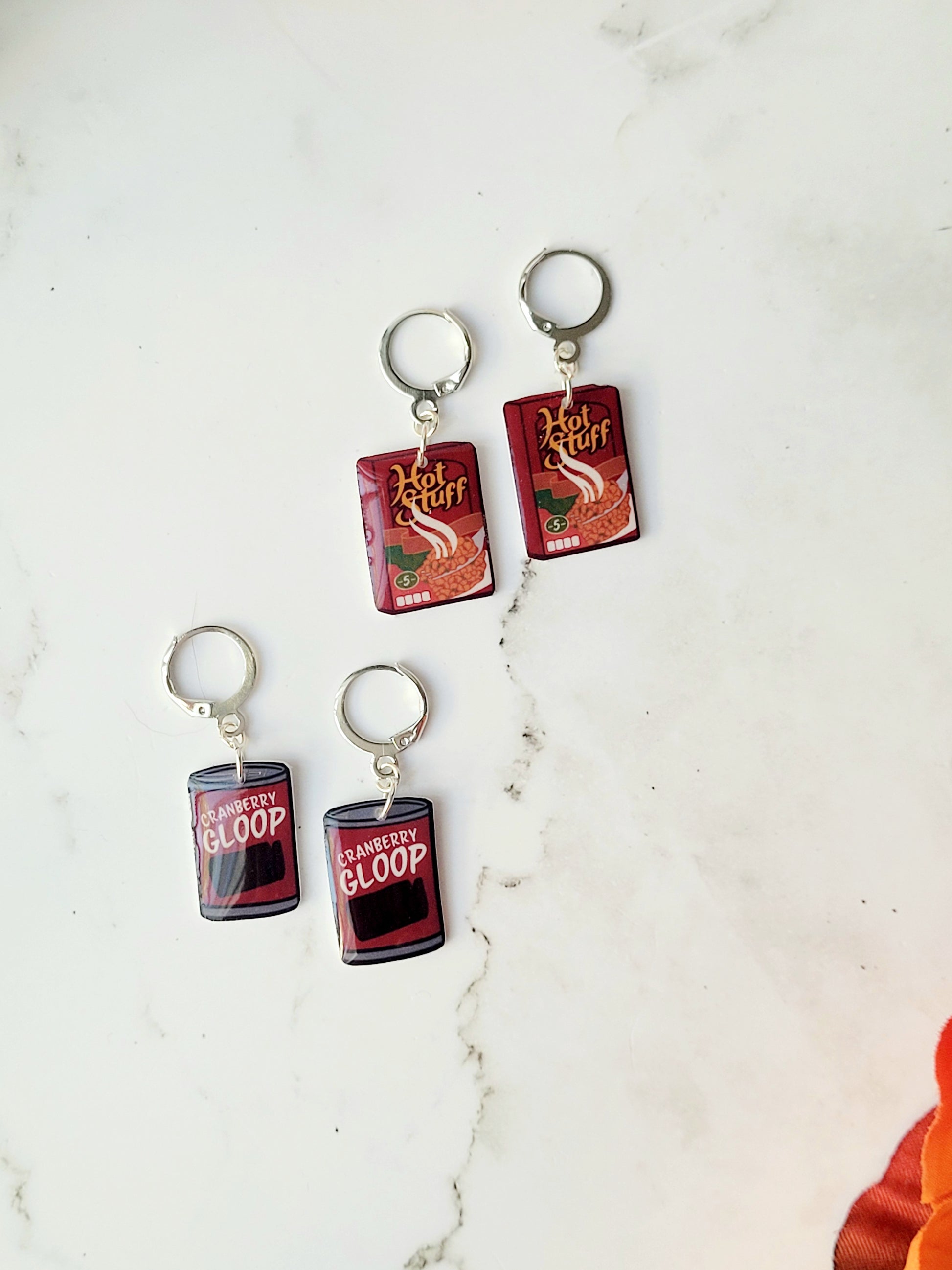 Close up of cranberry sauce and stuffing box earrings on a marble background with fall foliage.