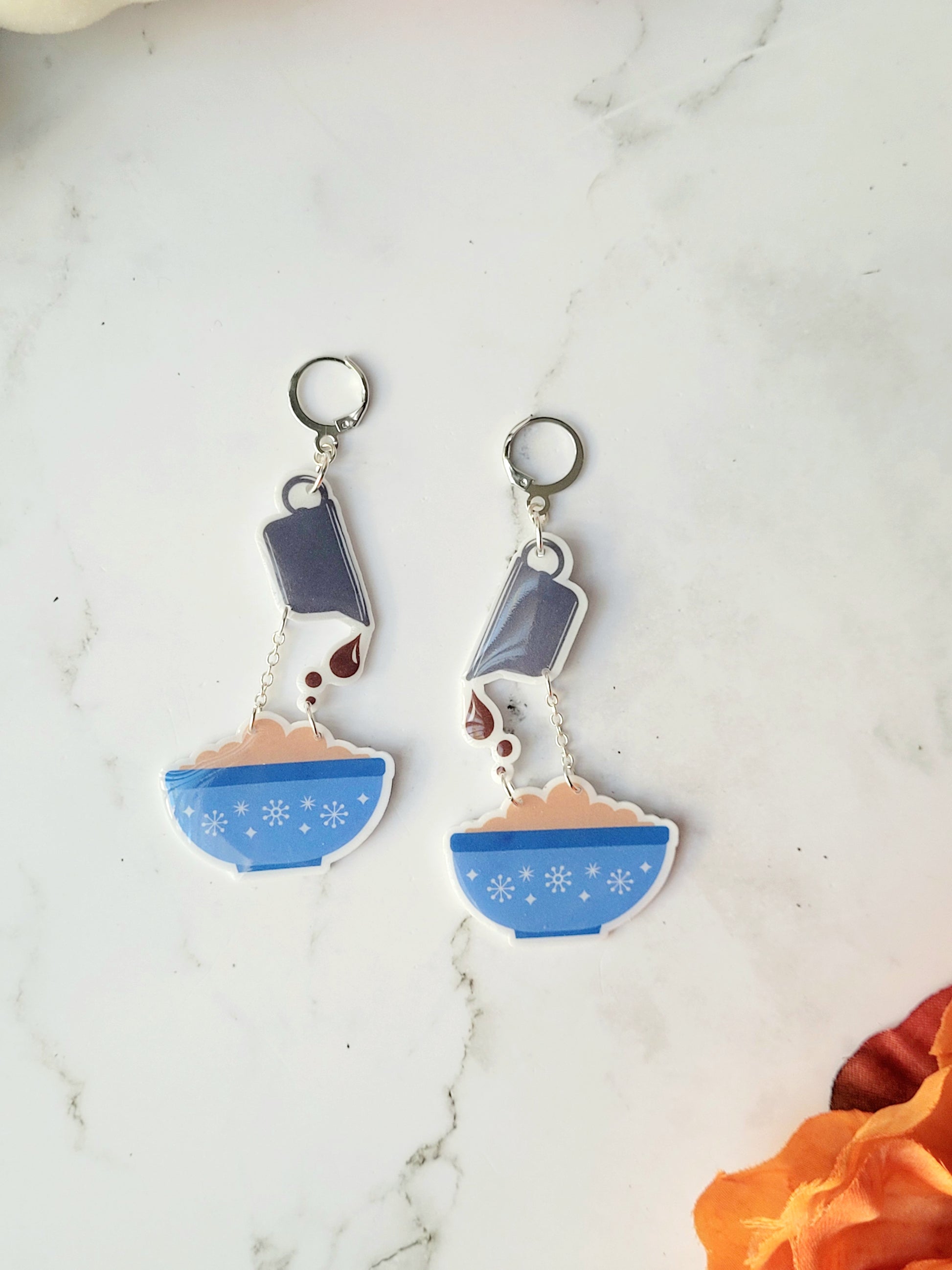 close up of mashed potato and gravy themed earrings on a marble background.