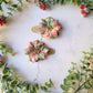 Christmas themed plaid poinsettia hair clip on a marble background surrounded by foliage.
