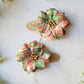 close up of the Christmas themed plaid poinsettia hair clip  on a marble background surrounded by foliage.