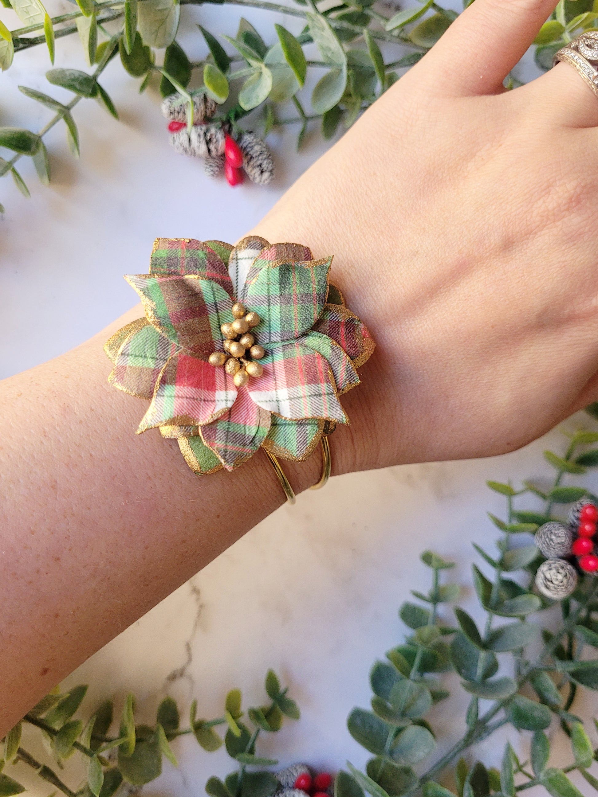 Christmas themed plaid poinsettia bracelet on a wrist for size reference. 