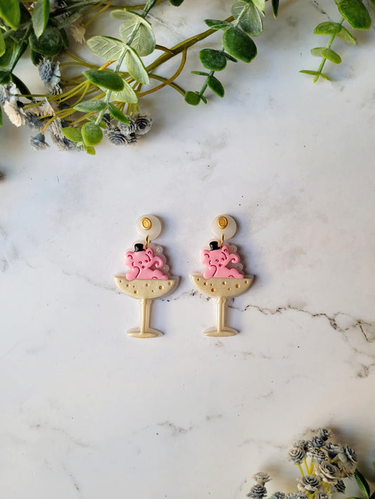 Pink Elephant in a champagne coupe earrings on a marble background . 