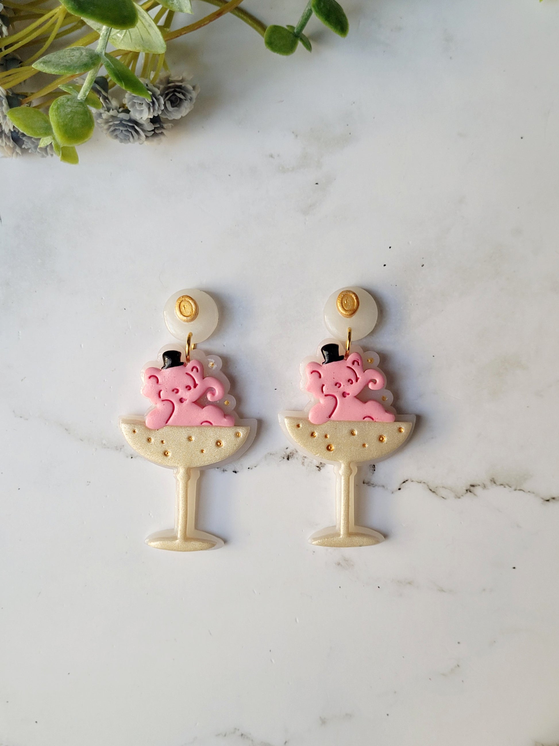 close up of Pink Elephant in a champagne coupe earrings on a marble background . 