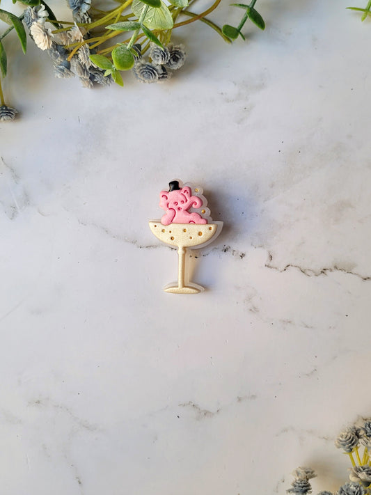 Pink Elephant in a champagne coupe brooch on a marble background .