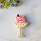 close up of Pink Elephant in a champagne coupe brooch on a marble background .