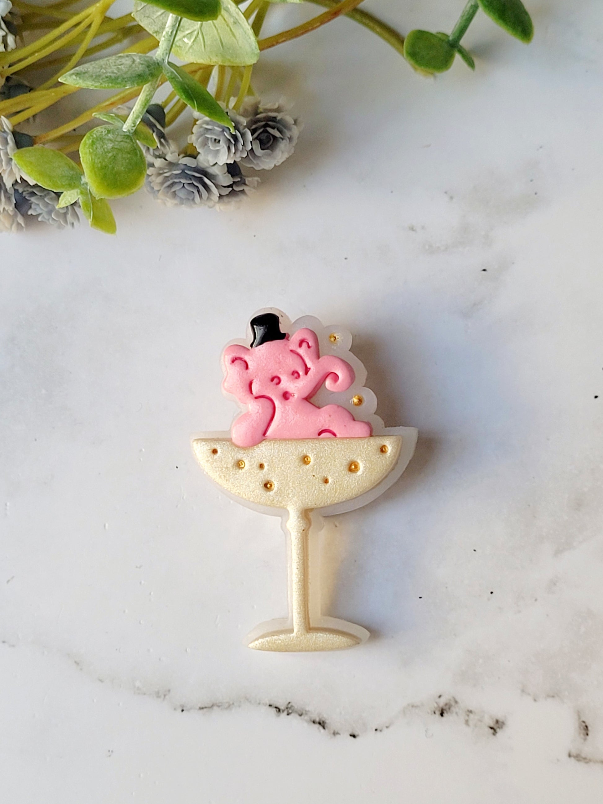 close up of Pink Elephant in a champagne coupe brooch on a marble background .