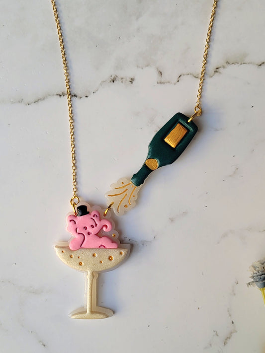 close up of Pink Elephant in a champagne coupe with a champagne bottle necklace