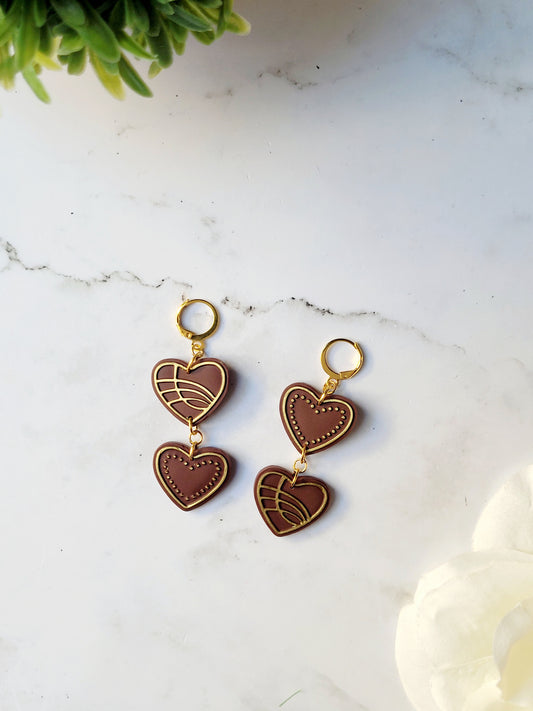close up of Chocolate and gold heart truffle earrings on a white background.