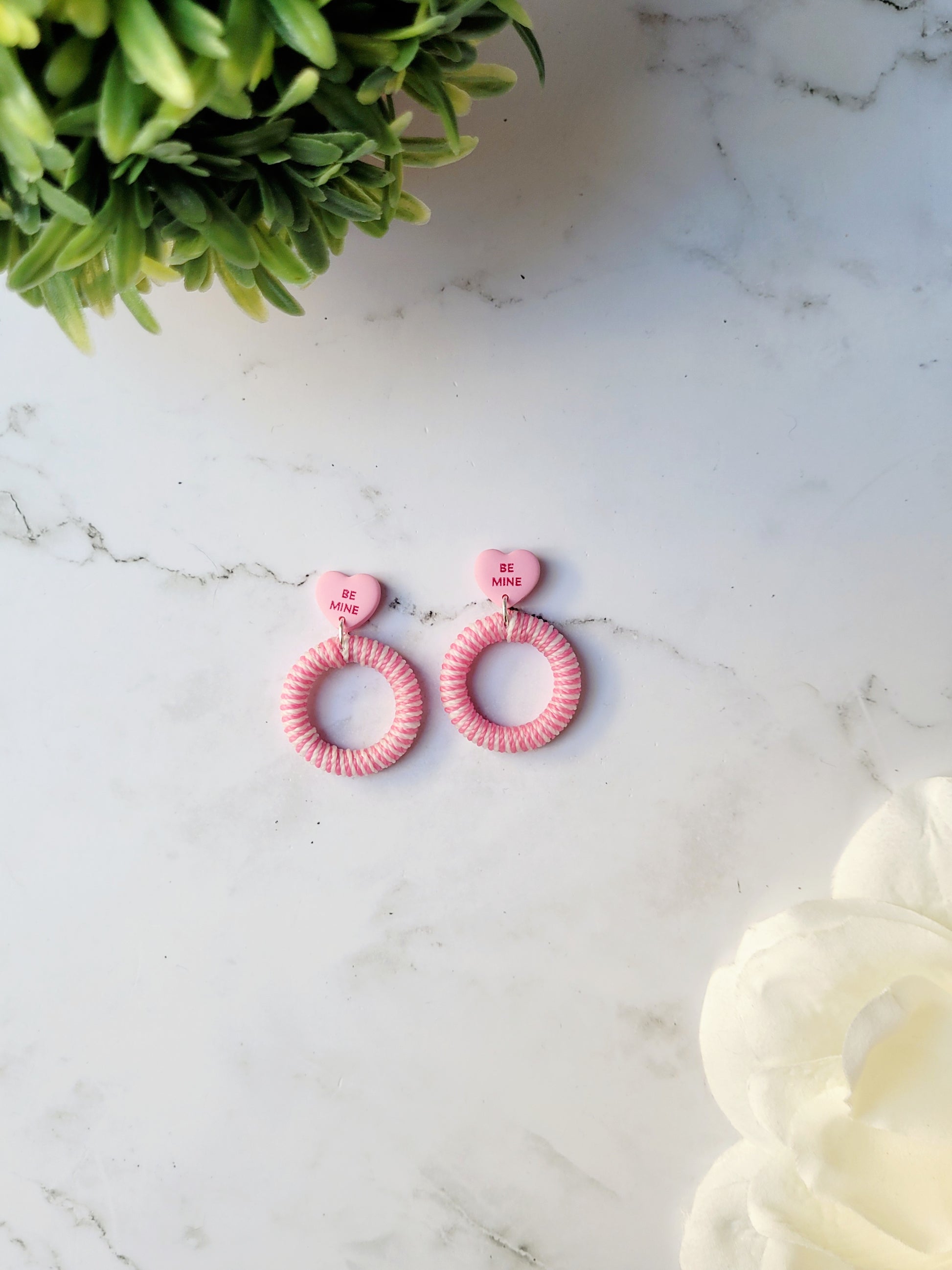 pink and white striped hoops with a pink candy heart stud on a marble background with foliage 