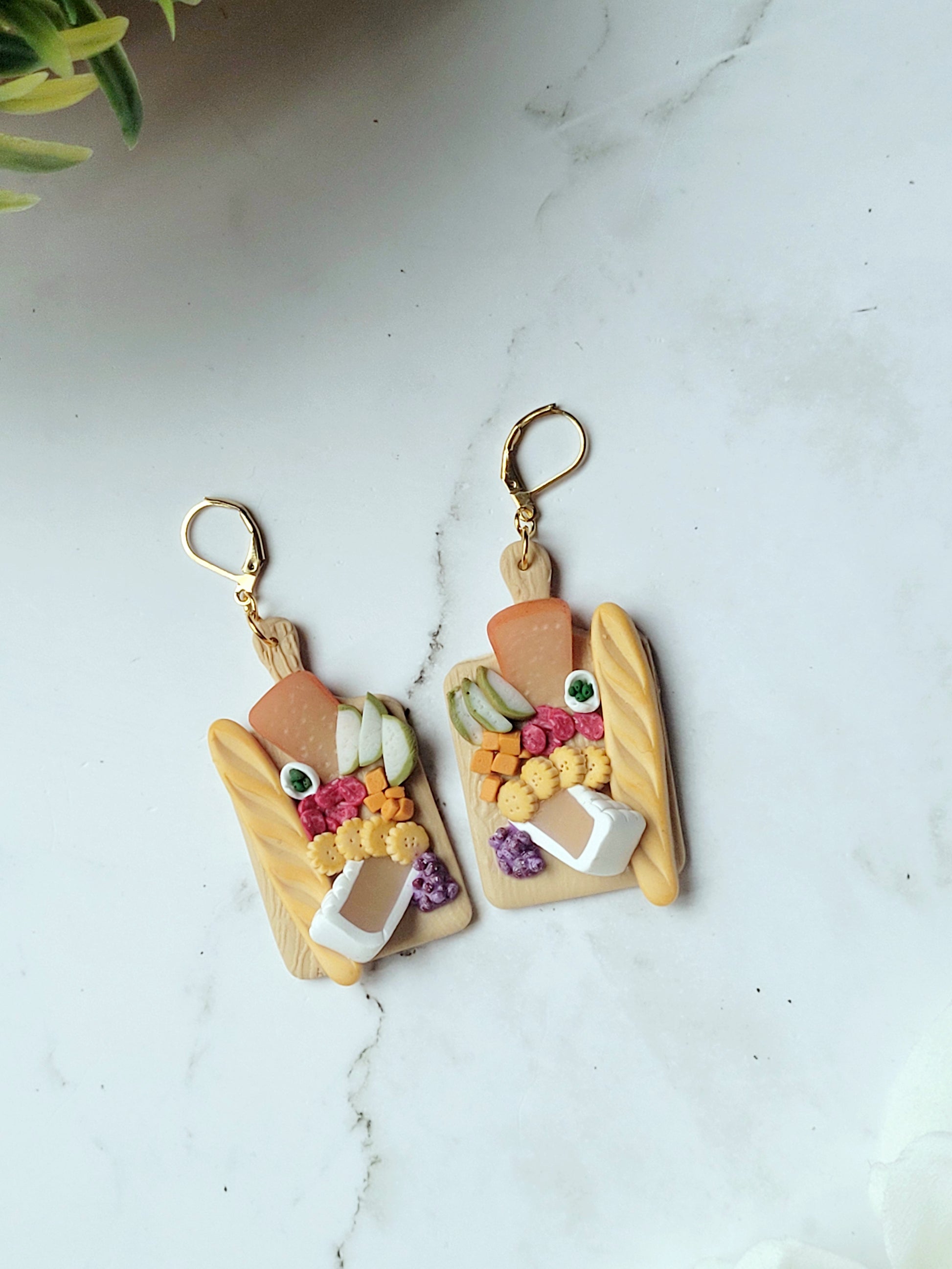 close up of charcuterie board earrings on a white marble background.