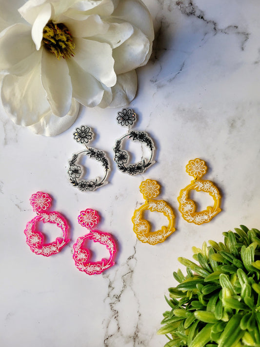 Ditsy floral hoops in white, pink, and yellow on a marble background. 