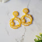 close up of Ditsy floral hoops in yellow on a marble background.