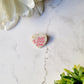 white pearl heart pin with self love club in pink on a marble background. 