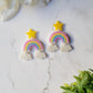 close up of rainbow dangle earrings with a star stud and cloud charms on a marble background