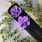 two purple pansy flower bracelets on a black velvet holder