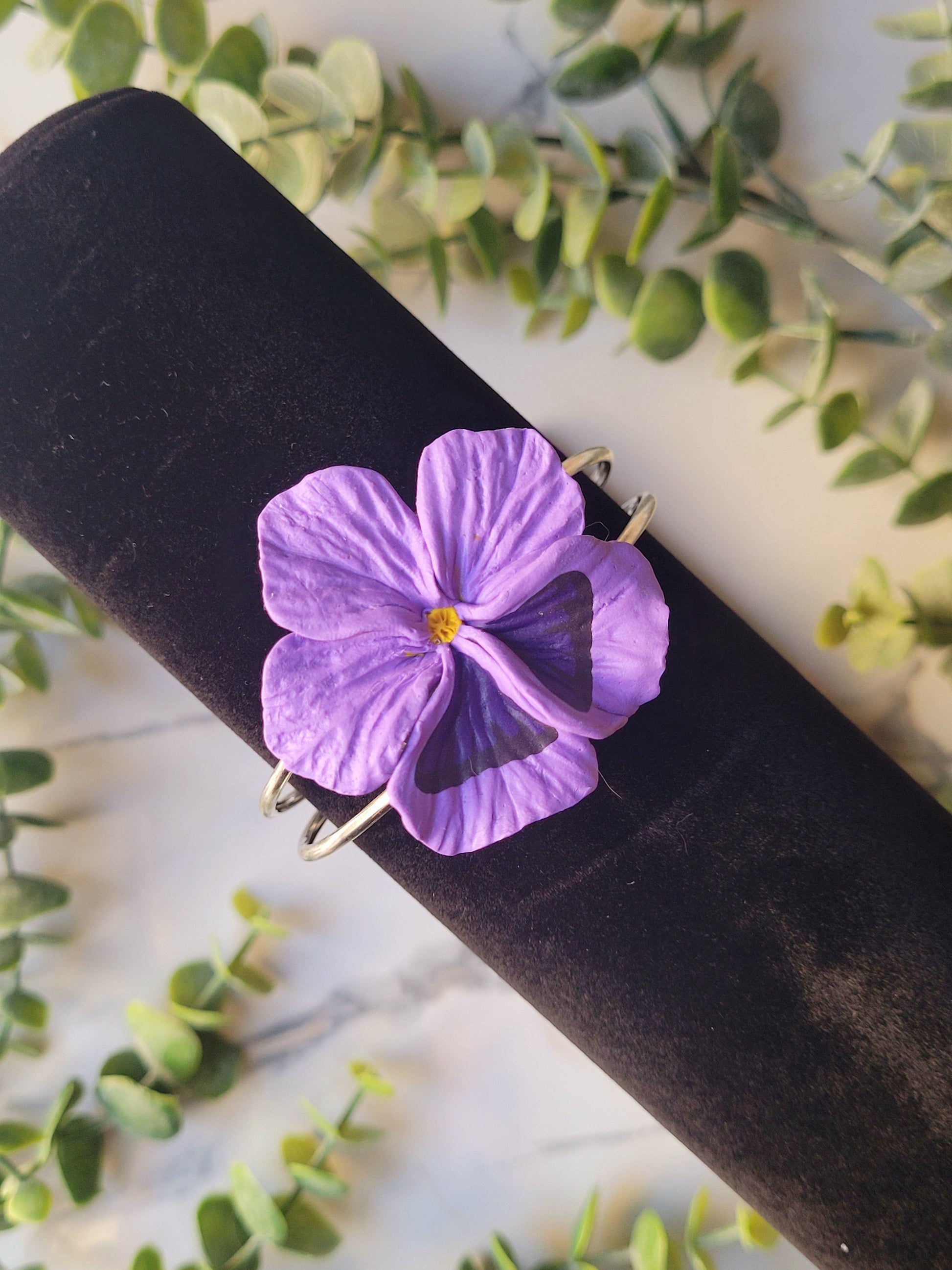 light purple pansy flower bracelet on a black velvet holder. 