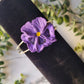 dark purple pansy flower bracelet on a black velvet holder.