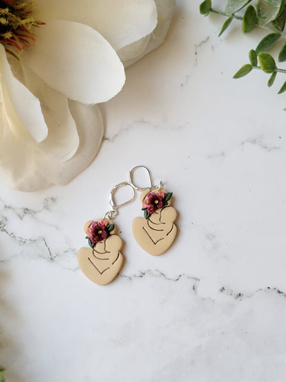 Light skin toned mother and child earring with flowers on a marble background 