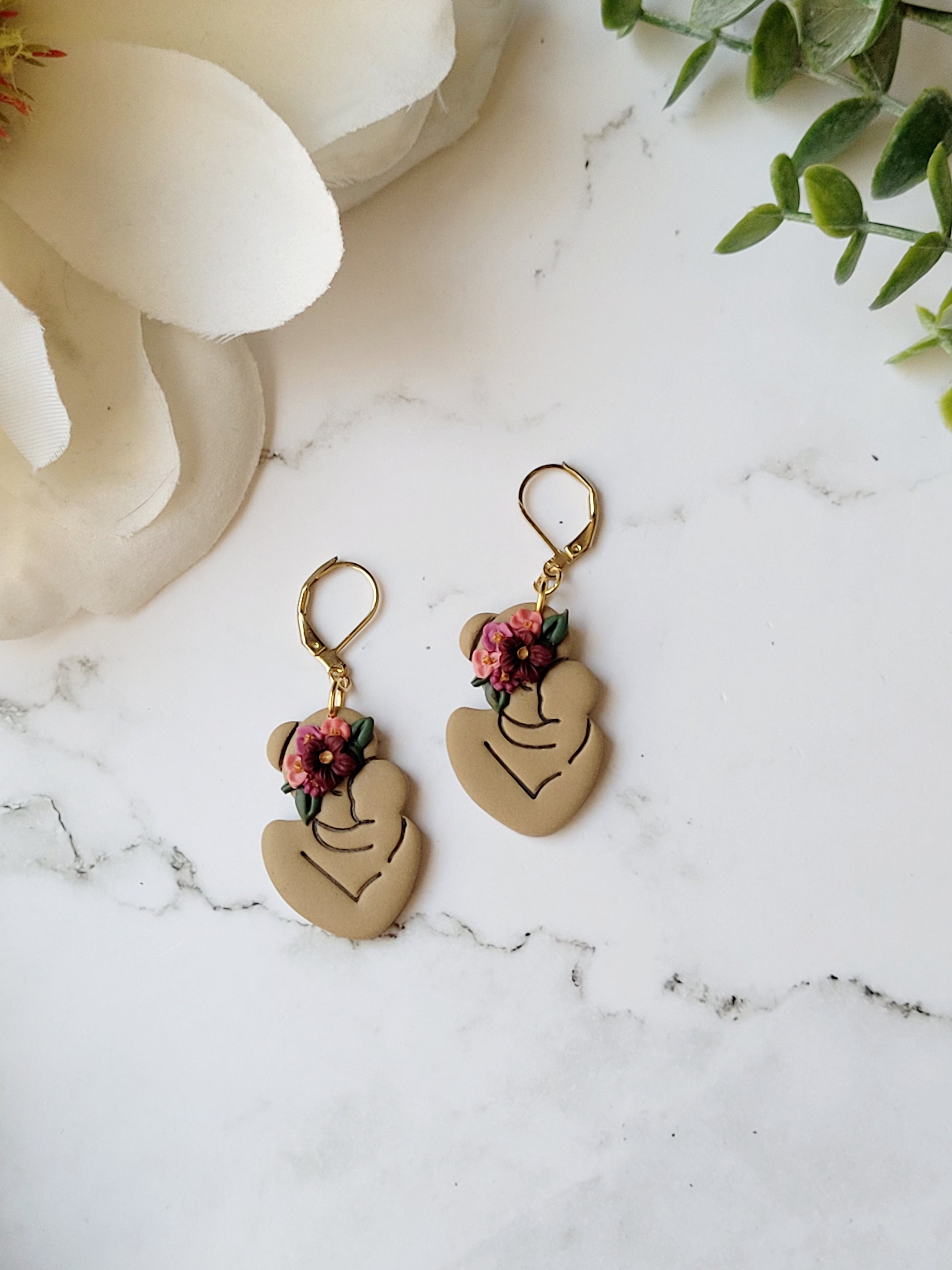 medium skin toned mother and child earring with flowers on a marble background