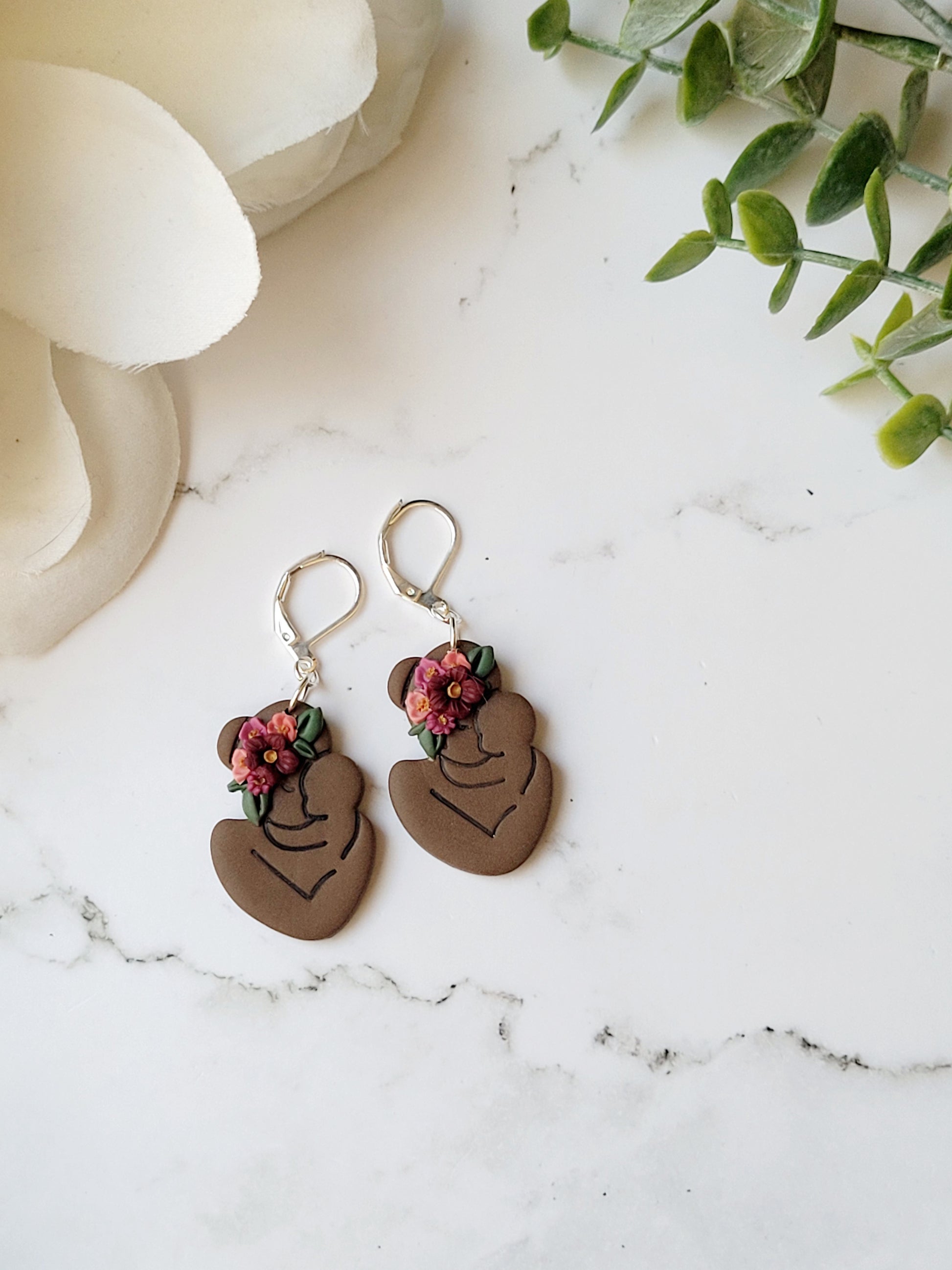 dark skin toned mother and child earring with flowers on a marble background