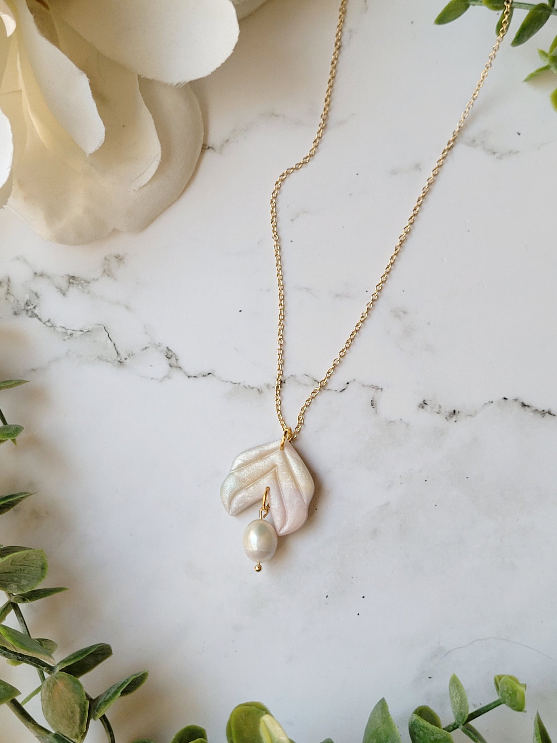 close up of faux mother of pearl pendant  with fresh water pearl accent on a marble background
