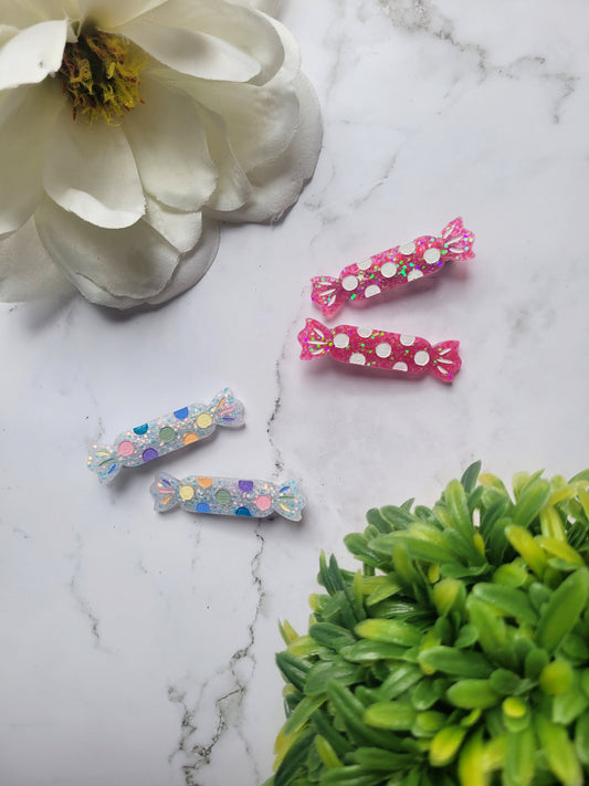 White and Hot Pink candy shaped hair clips on a marble background with foliage. 