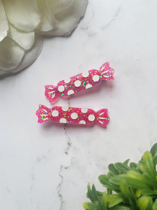 close up of hot pink candy shaped hair clip on a marble background. 