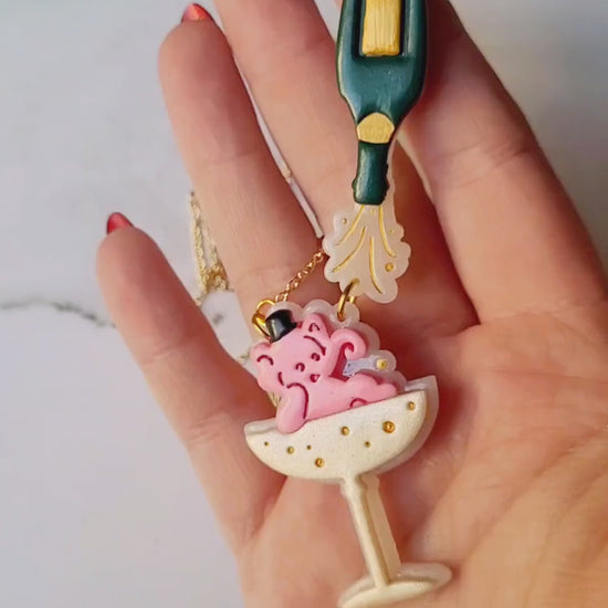 video close up of Pink Elephant in a champagne coupe with a champagne bottle necklace 
