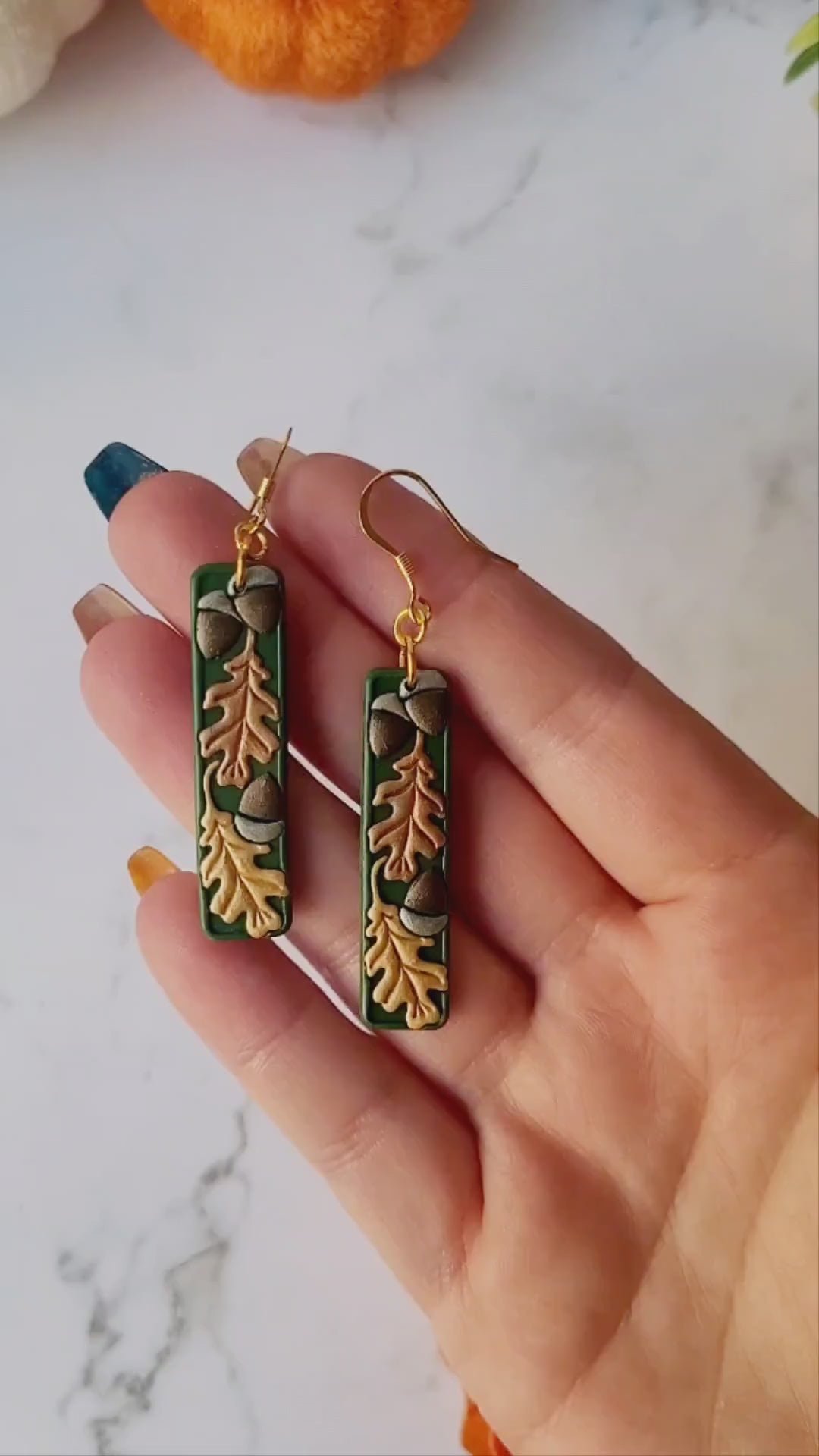 video close up of the Green bar shaped earrings with metallic acorns and oak leaves.