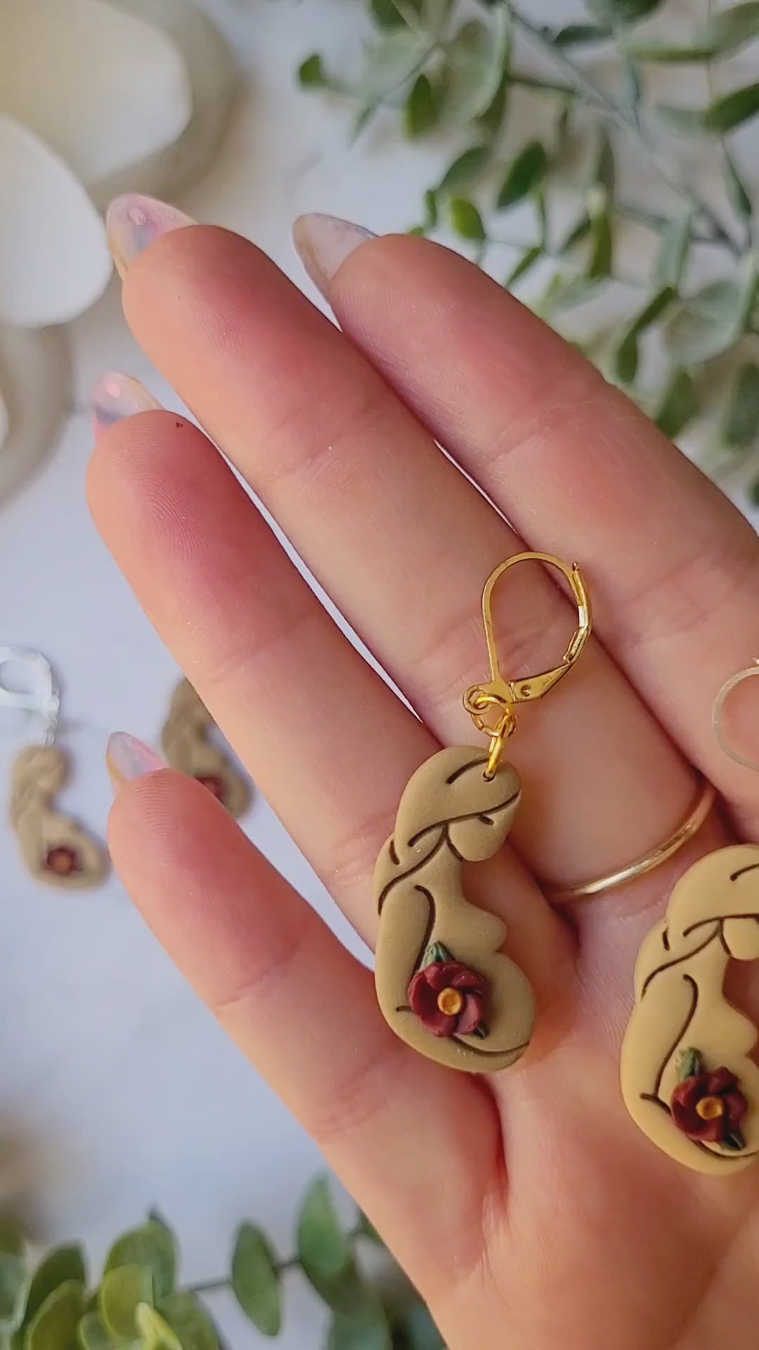 video of three different skin toned of pregnant women earrings on a marble background.