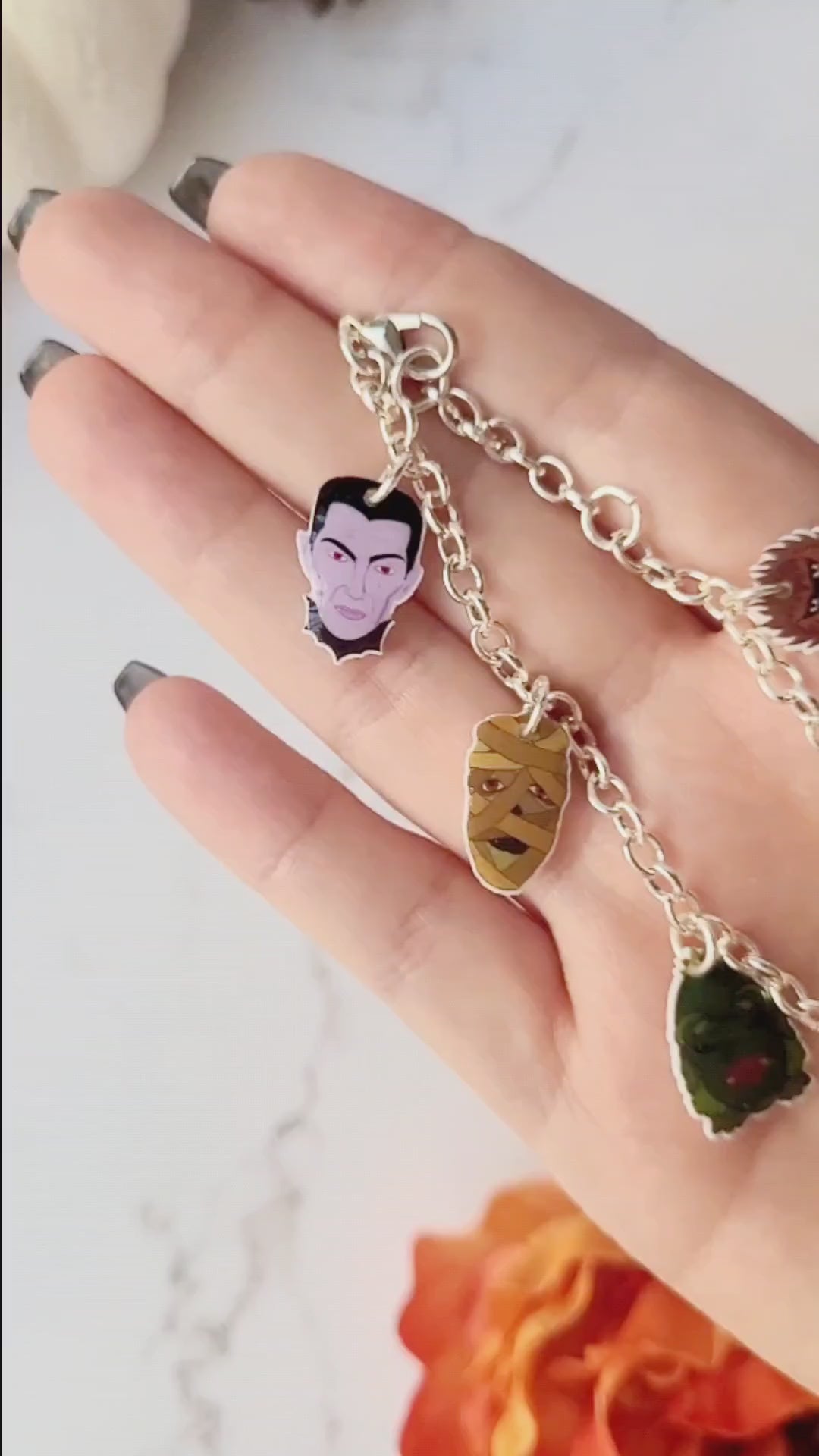 video close up of universal monster charm bracelet on a marble background .