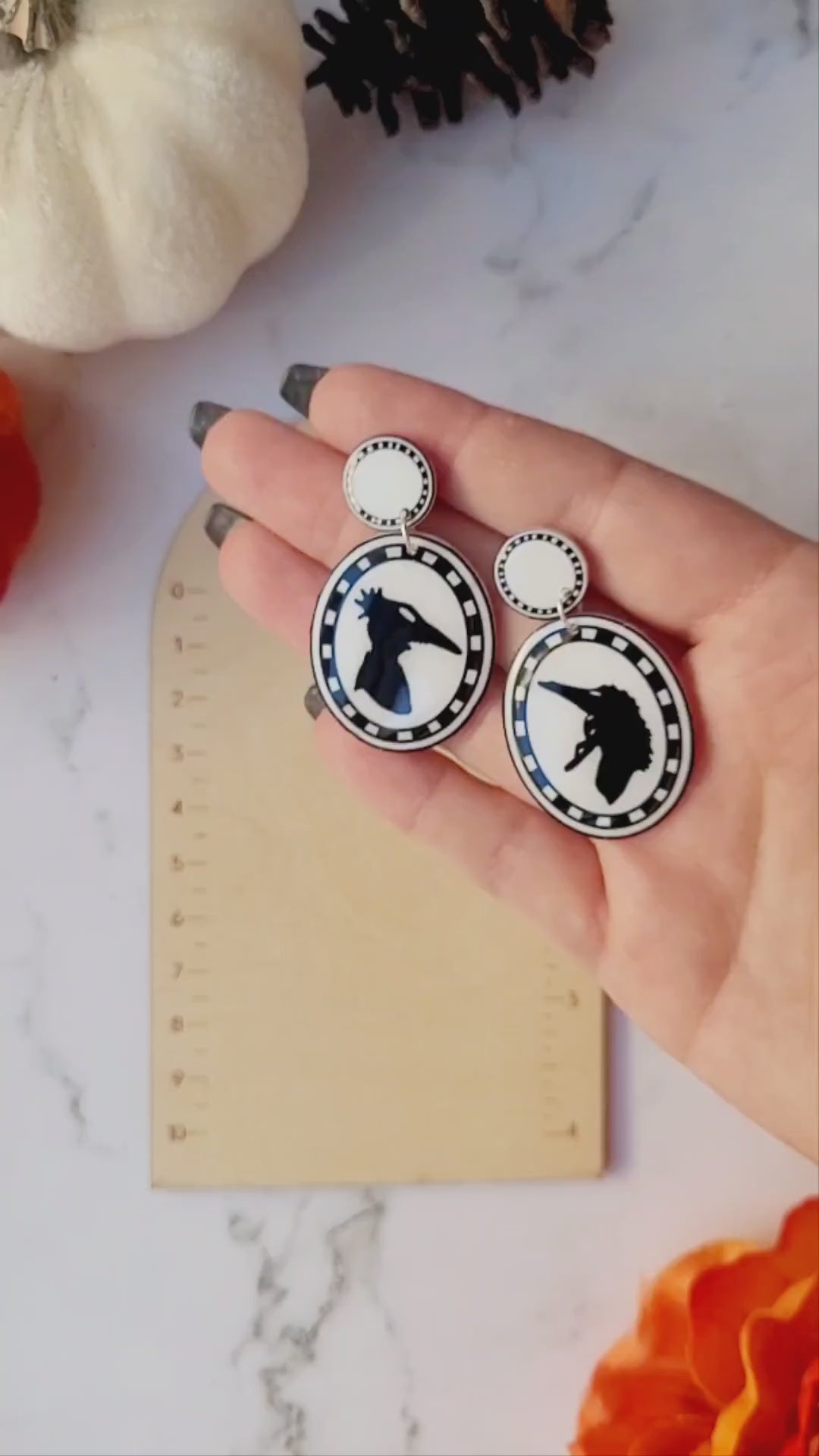 video close up of Beetlejuice silhouette earrings on a ruler  background.