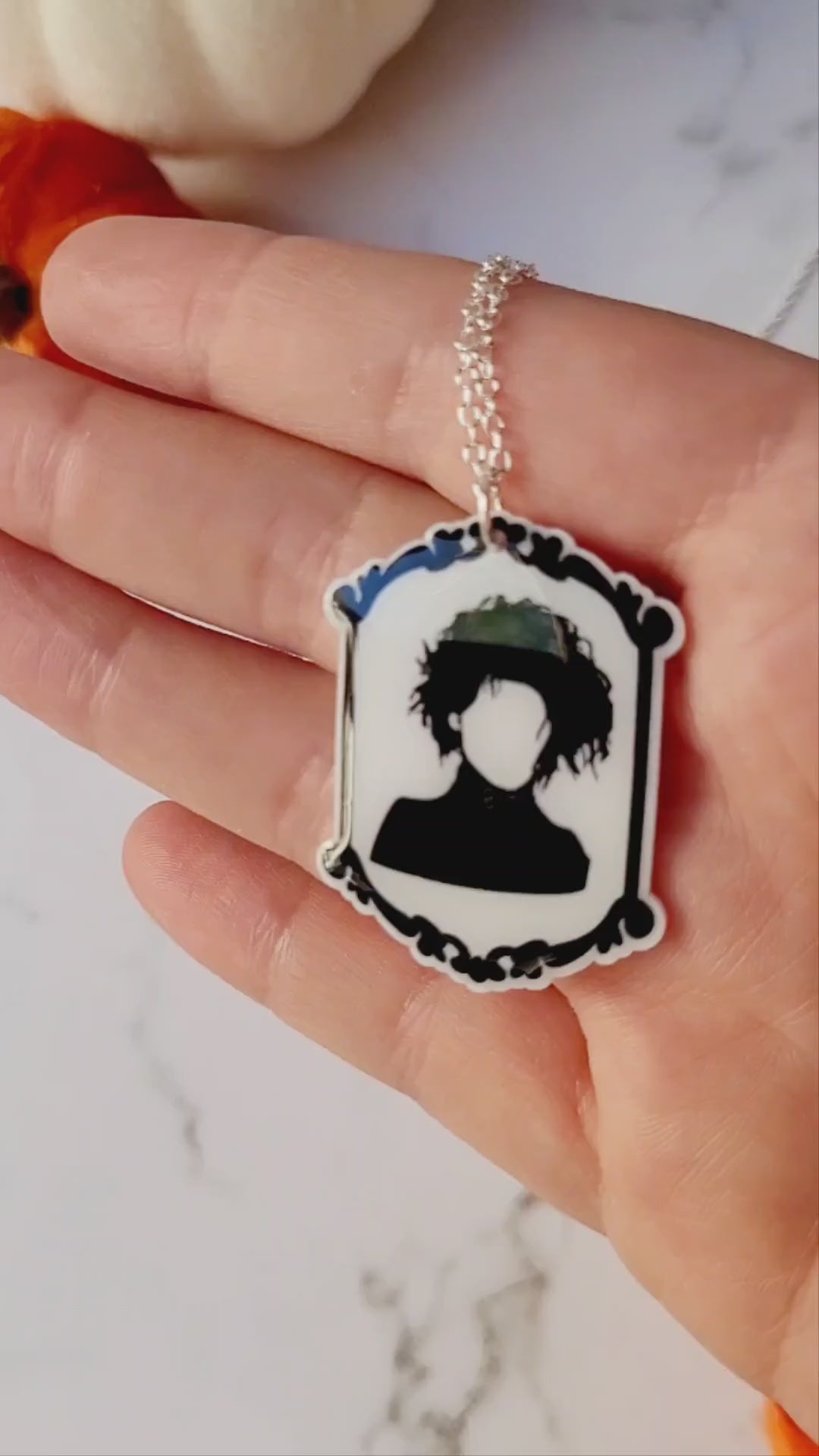 video close up of Edward Scissorhands themed pendant on a marble background.