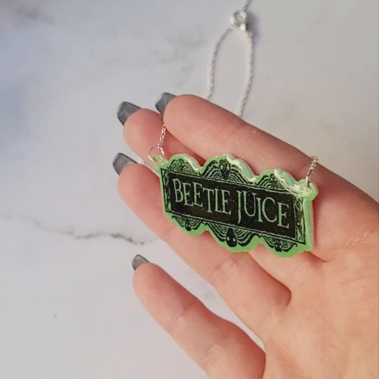 video close up of Beetlejuice logo necklace on a white marble background 